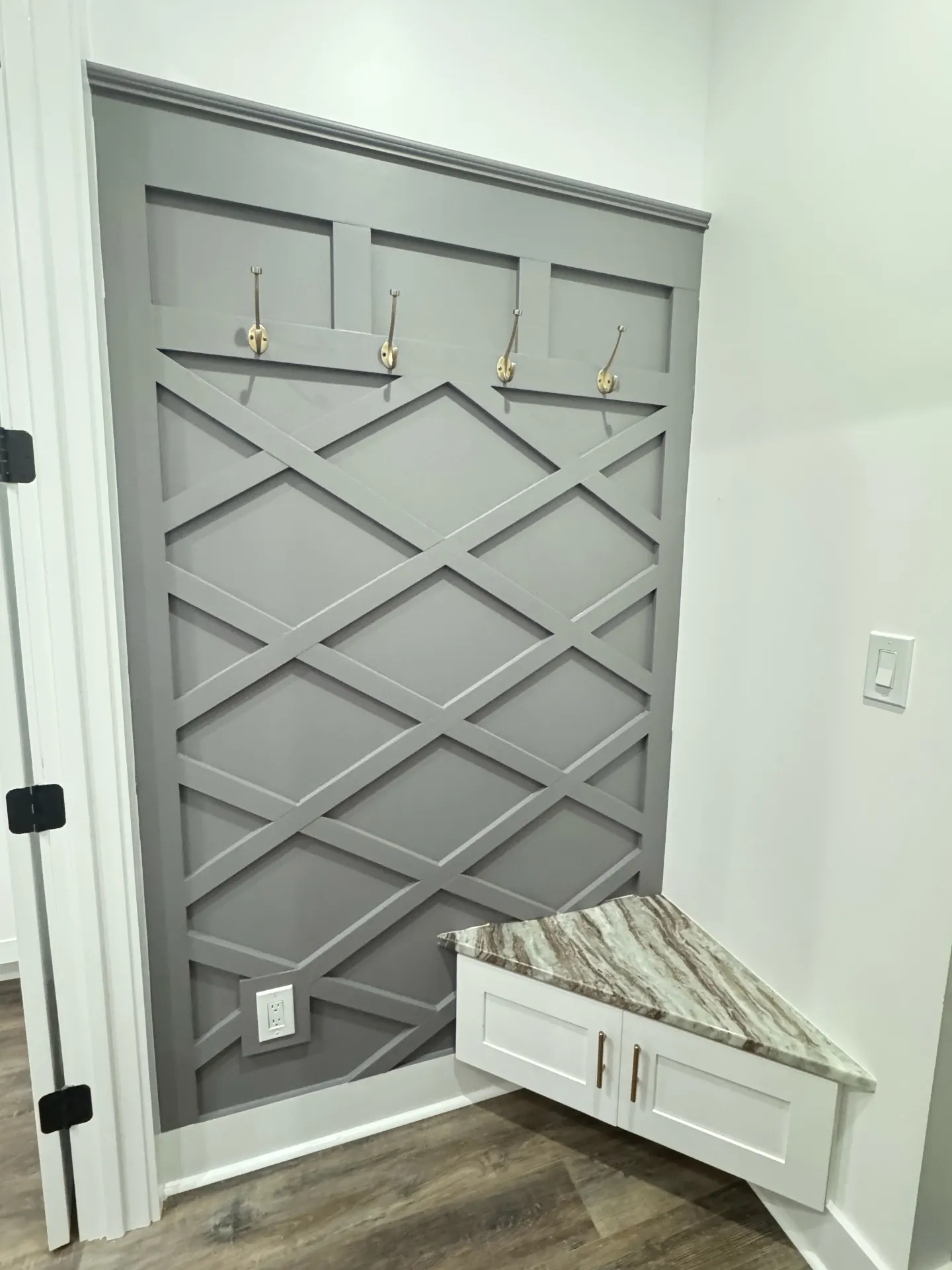 Custom gray mudroom with lattice detail, hooks, and marble corner bench